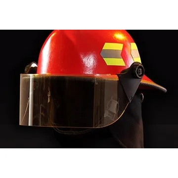 Close-up front left side view of a Fire-Dex® Modern Helmet in red with visor down, emphasizing shell texture, visor, and reflective safety trim.