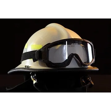 Close-up front right side view of a Fire-Dex® Modern Helmet in white with goggles mounted on the helmet, showing protective shell, accessories, and reflective trim.
