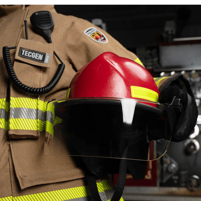 Close-up of a firefighter holding a Fire-Dex® Modern Helmet in red with visor down by their side, showing helmet size, shape, ergonomic design, and integrated visor.