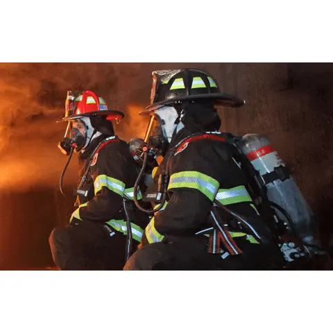 Two firefighters wearing Fire-Dex® H41 Interceptor with STEDAIR® Prevent jackets inside a burning building, demonstrating teamwork, protective coverage, and visibility in hazardous conditions.