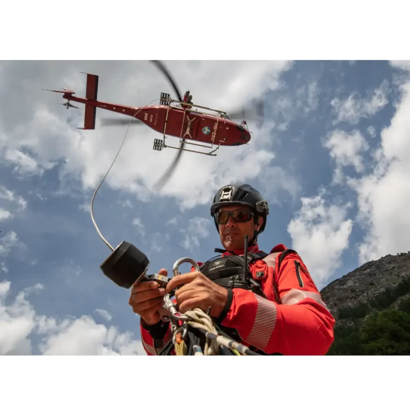 Rescuer wearing Team Wendy® SAR™ Backcountry Helmet with helicopter overhead, demonstrating readiness in emergency response and search operations.