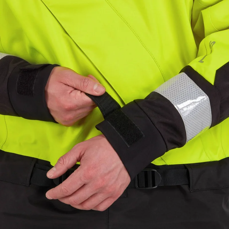 Closeup of a man wearing the NRS Extreme SAR Dry Suit in safety yellow, tightening the Velcro wrist straps for a secure watertight seal.
