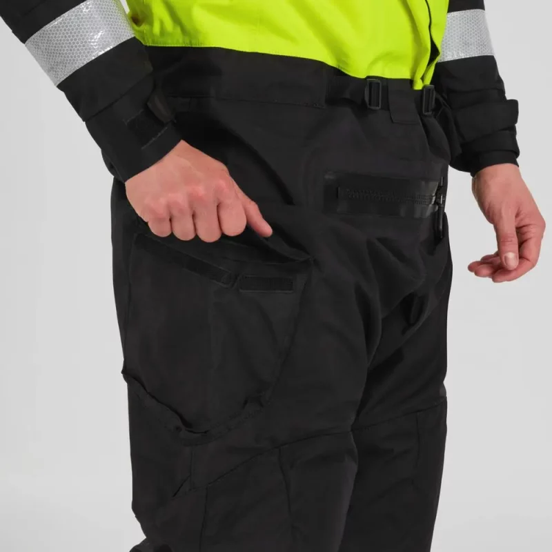 Closeup of a man wearing the NRS Extreme SAR Dry Suit in safety yellow, with one hand in the waterproof thigh pocket.