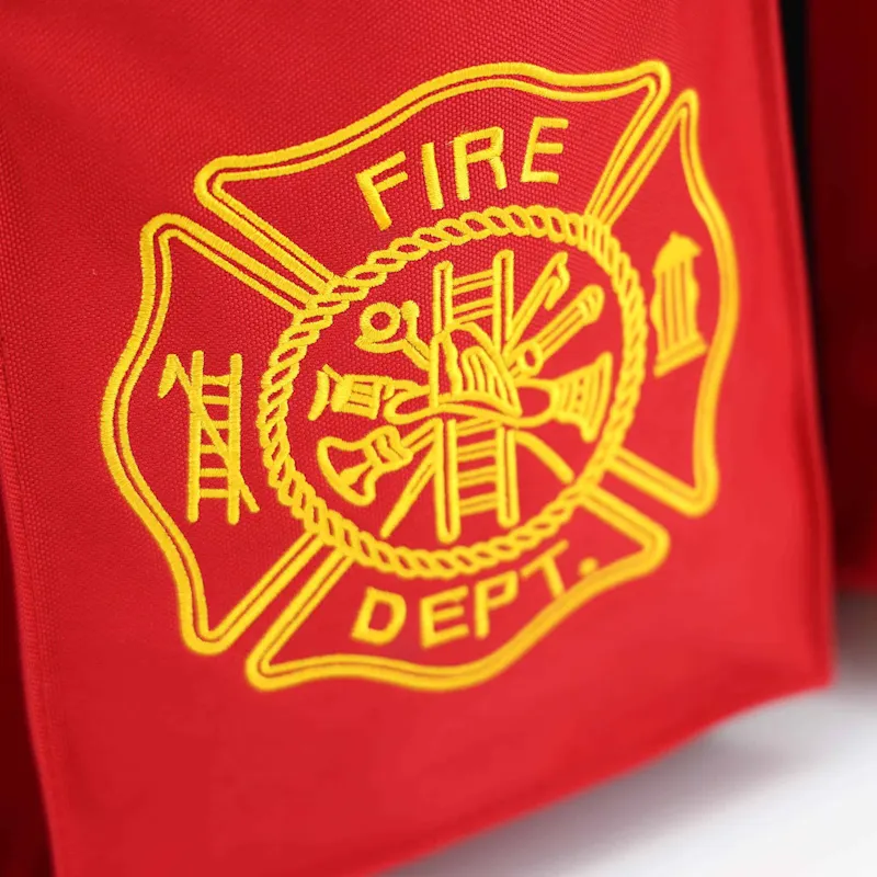 Close-up of the red Lightning X LXFB20 turnout gear bag's gold embroidered Fire Dept. Maltese cross emblem with ladder, hydrant, and tools.