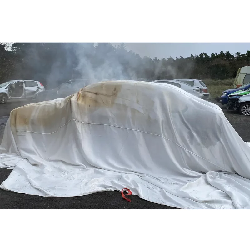 T-ISS FI-BL0906 EV Fire Blanket in use on a car — high-temperature silica fire blanket deployed over an electric vehicle to isolate and suppress fire, preventing spread and reducing smoke during emergency response.