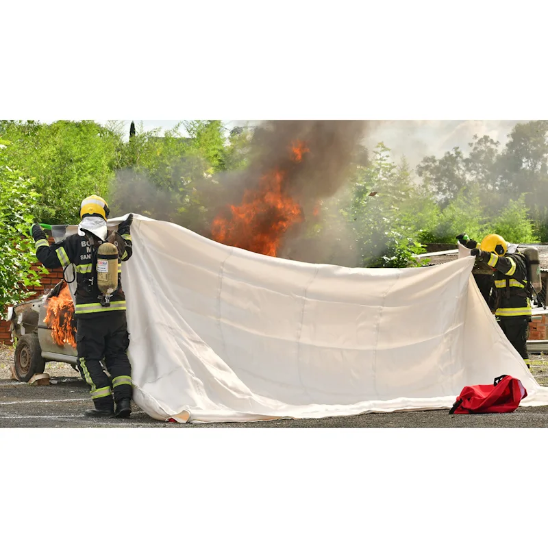 Firefighters using T-ISS Ultimate Fire Blanket to smother burning vehicle during training exercise.