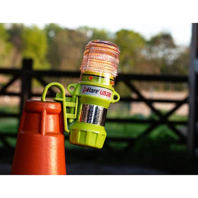 Eflare UB280 LED safety beacon with hook attachment clipped to a traffic cone for roadside hazard warning outdoors.