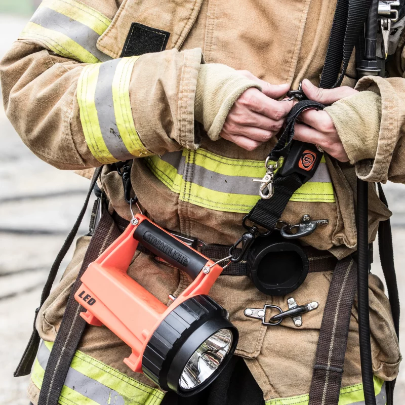 Firefighter carrying the Streamlight® Fire Vulcan® LED Lantern by its strap, demonstrating its portability and hands-free convenience during emergency operations.
