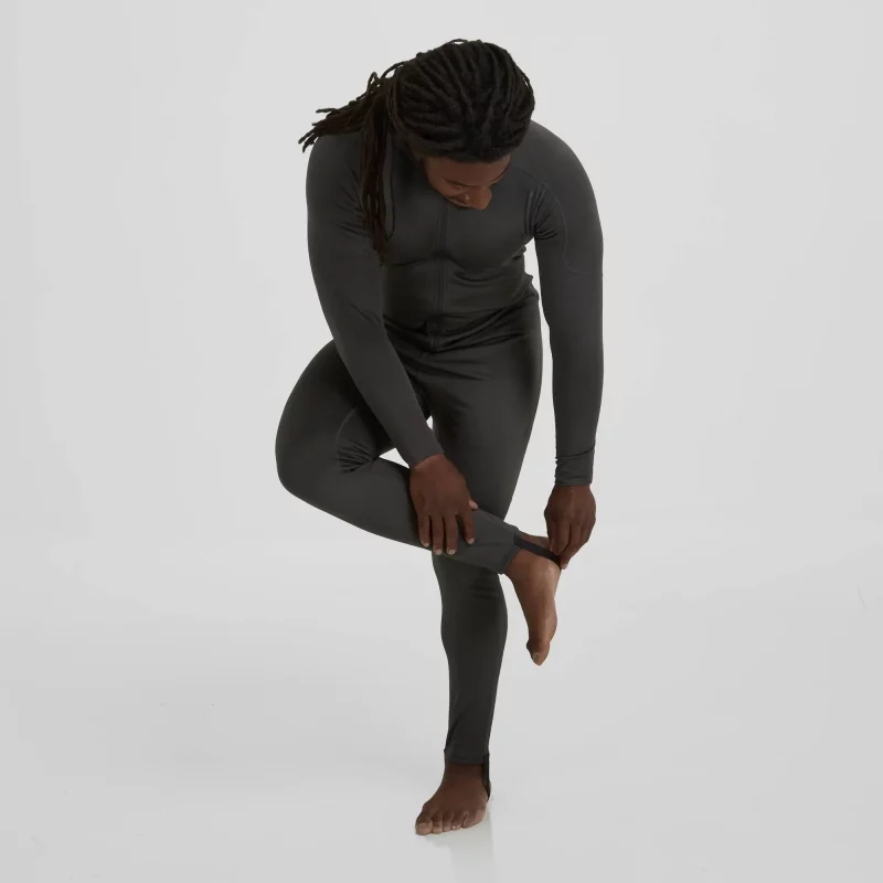 Front side view of a man wearing the NRS Men’s Expedition Weight Union Suit while adjusting the integrated foot stirrups, demonstrating secure fit and practical features.