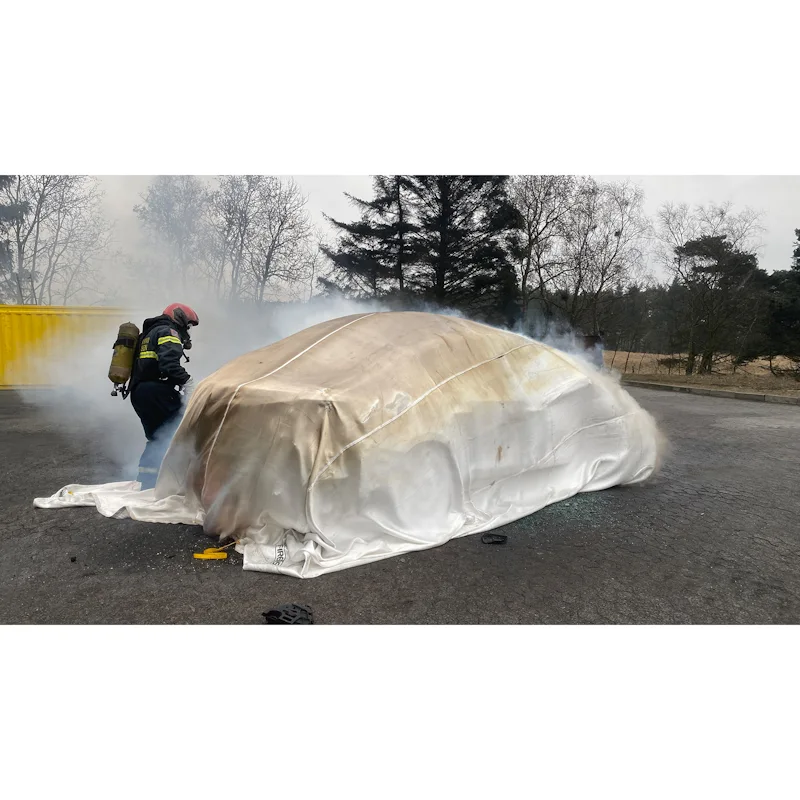 T-ISS Ultimate Fire Blanket fully covering a smoking vehicle during a firefighter training exercise.