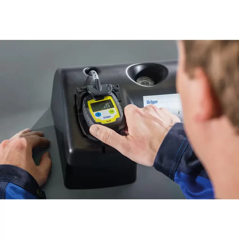A person holding the Dräger Pac® 6000 Single-Sensor Gas Detector configured for hydrogen sulfide (H₂S) detection, showing the device’s clear digital display and compact, rugged design.