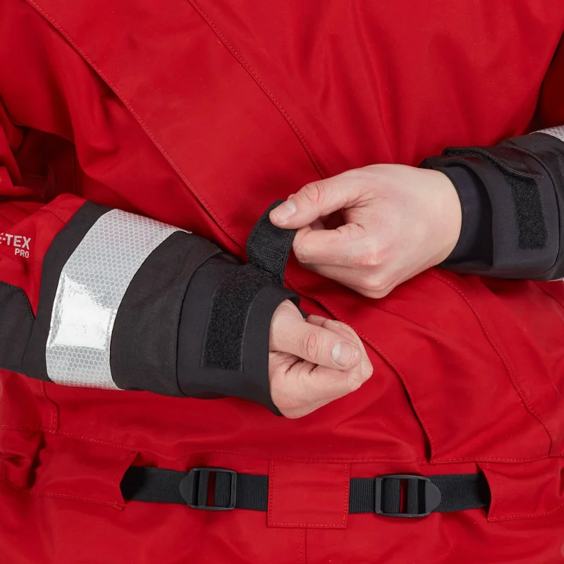 Closeup of a man wearing the NRS Ascent SAR Dry Suit in red, securing the Velcro wrist straps for a snug and waterproof fit.