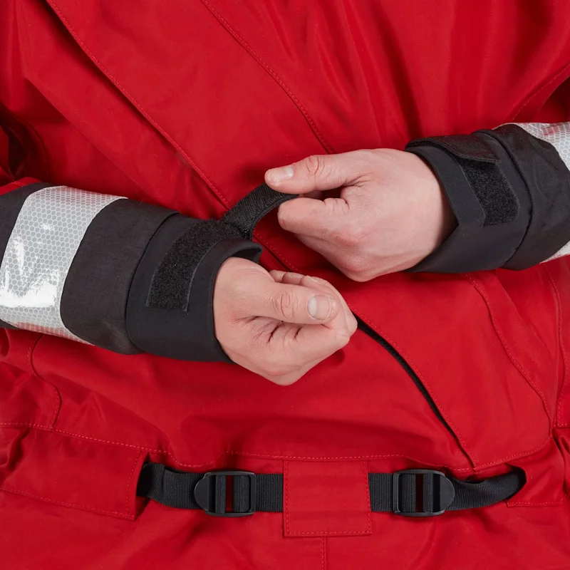 Closeup of a man wearing the NRS Extreme SAR Dry Suit in red, tightening the Velcro wrist straps for a watertight seal.