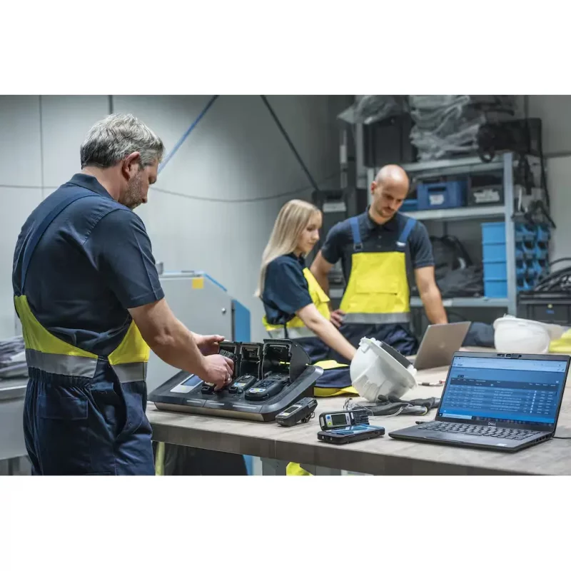 Worker placing Dräger X-am® multi-gas detectors into a detector station for charging or calibration on site.