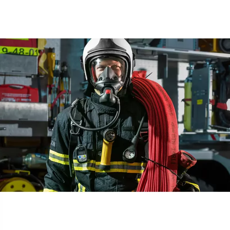 A firefighter in full gear with the Dräger Pac® 6500 Single-Sensor Gas Detector for carbon monoxide (CO) securely clipped to their uniform, providing real-time hazardous gas monitoring during emergency response operations.