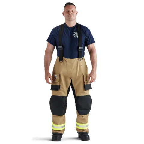 Front view of firefighter wearing tan Fire-Dex® AeroFlex™ turnout gear, emphasizing reinforced chest protection and adjustable closures for secure fit.