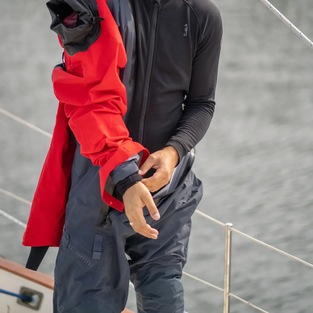 Man removing the Mustang Survival® Men’s Hudson CCS Dry Suit in Admiral Red, highlighting the suit’s durable waterproof fabric and ergonomic design during doffing.
