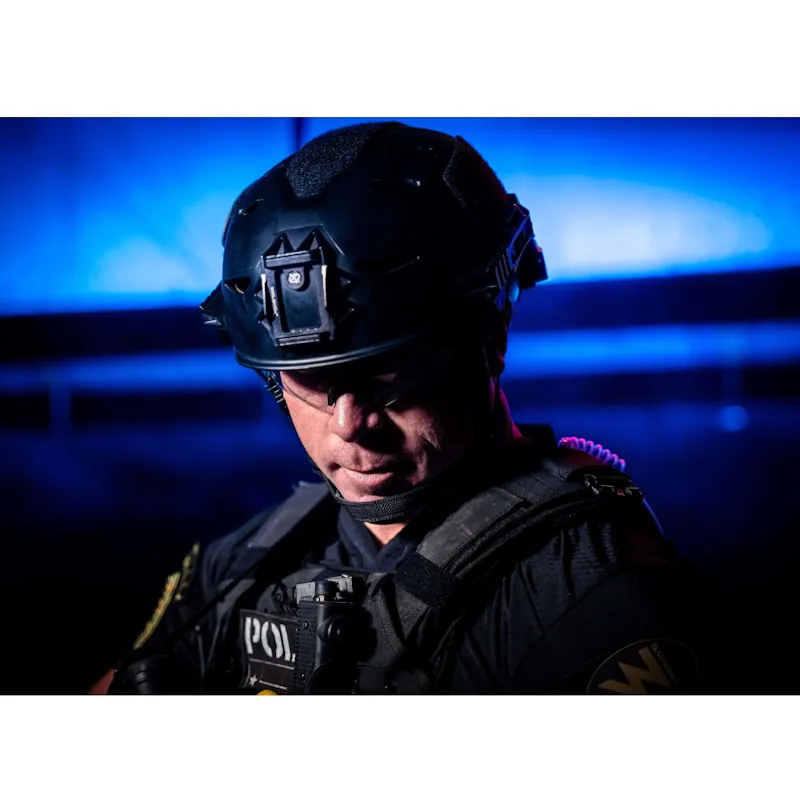 Policeman wearing the Team Wendy® EXFIL® LTP Bump Helmet during duty operations, equipped with tactical gear and radio headset.