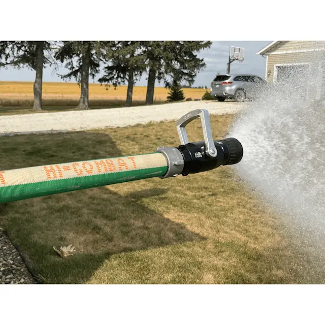 Green BullDog™ Hi-Combat® Firefighting Hose actively spraying water, demonstrating high-performance firefighting capability.