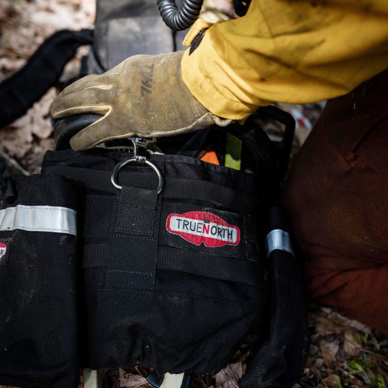 Close-up of True North Gear Chainsaw Pack showing durable fabric, reinforced stitching, multiple storage compartments, and chainsaw securing straps.