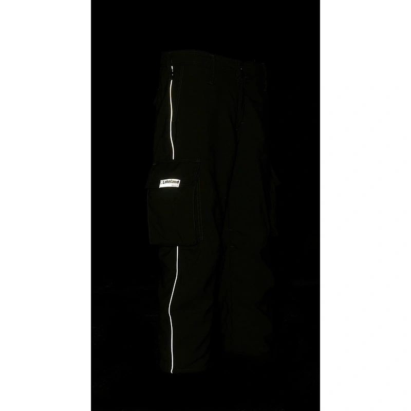 Lakeland® Wildland Fire Coverall in spruce green shown in low-light conditions highlighting high-visibility reflective striping and durable protective construction designed for enhanced safety in wildfire operations.