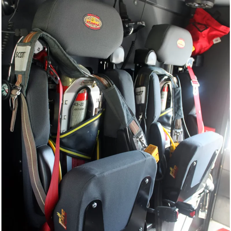 Two Ziamatic™ EZ-OUT SCBA Brackets mounted on a firetruck seat, each securely holding a cylinder with attached carrying straps for fast access during emergency response.