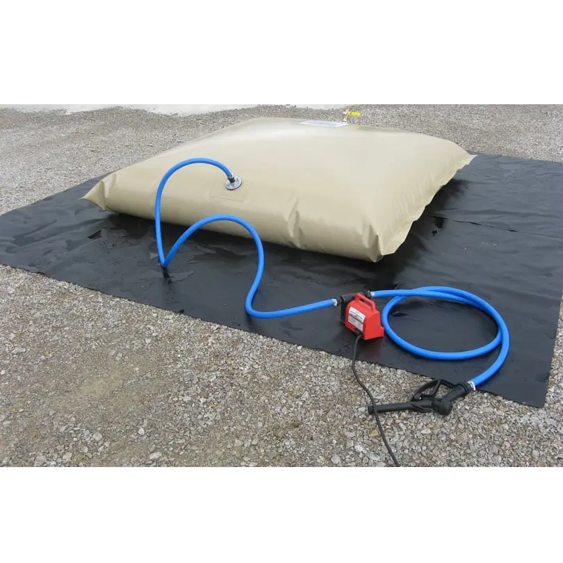 Tan pillow-style Husky® tank on a black Husky® ground tarp, connected to a red electric pump with blue hoses and a nozzle on a gravel surface.