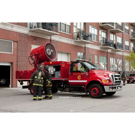 Side view of the Tempest Mobile Ventilation Unit MVU-48 mounted on a truck next to firefighters, demonstrating its large-scale airflow capability during emergency response operations.