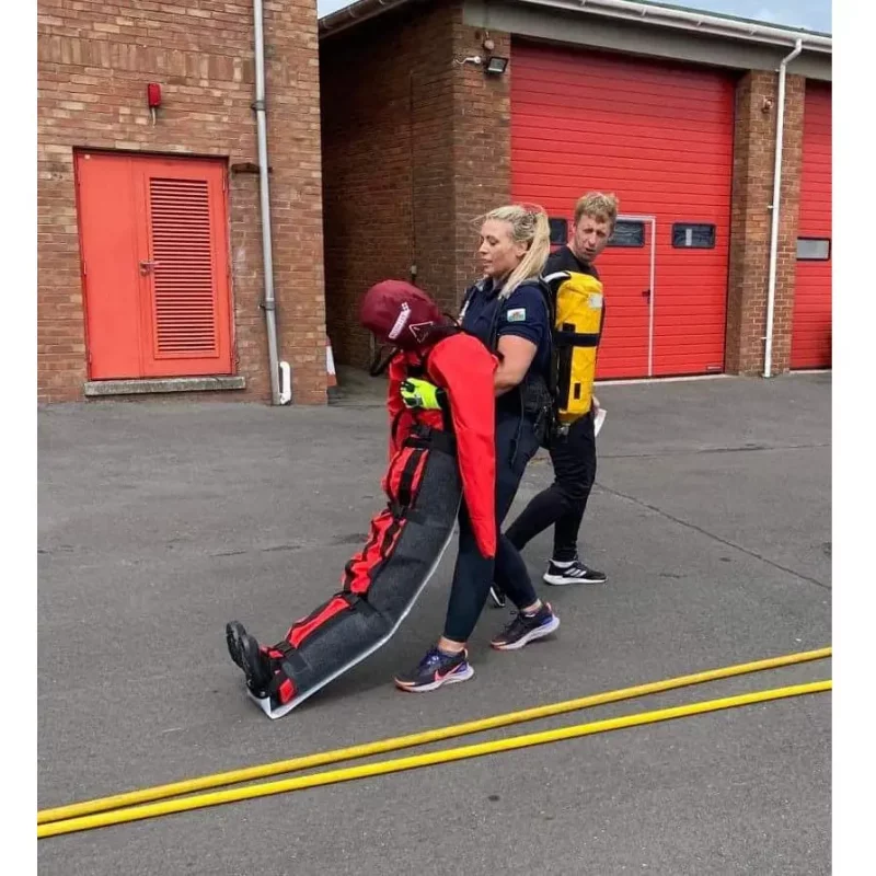A Ruth Lee™ Casualty Evacuation Manikin being carried outside by rescue personnel during an emergency evacuation training exercise.