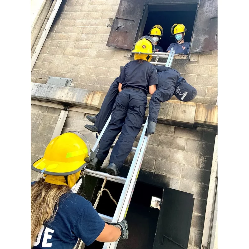 A Ruth Lee™ Fire House Training Manikin being rescued through a window during a simulated firefighter rescue training exercise.