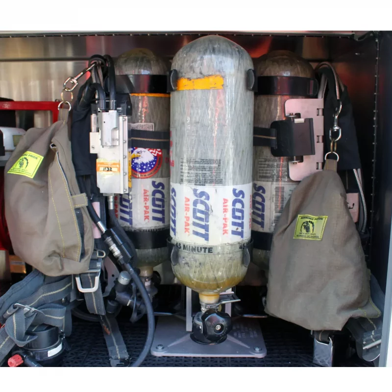 Close-up side view of a Ziamatic™ QUIC-INDEX Multiple Bracket Holder securely mounted on a firetruck, showcasing its heavy-duty quick-release brackets organizing cylinders and rescue equipment.