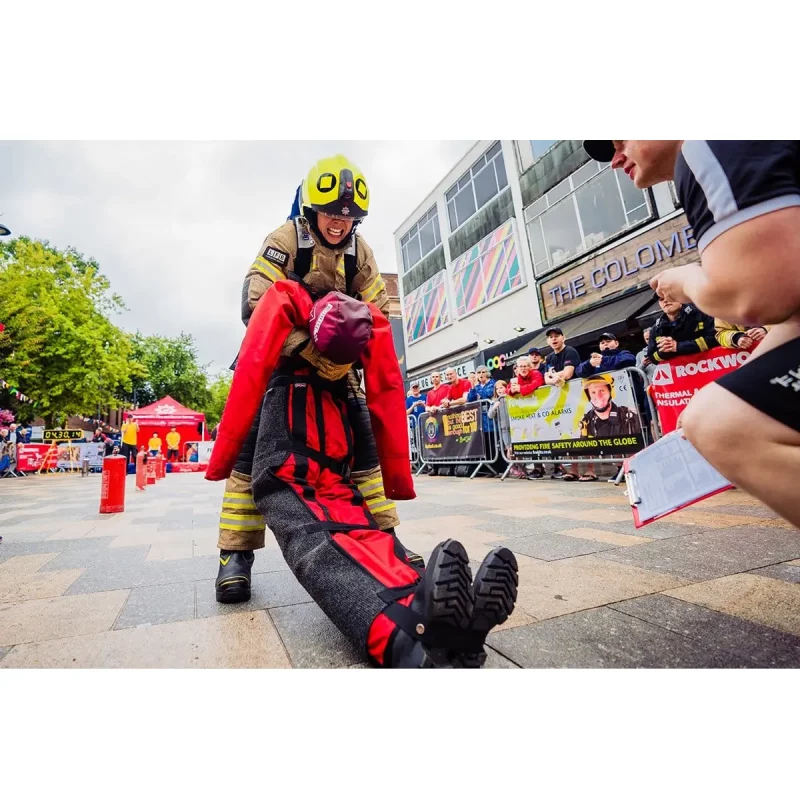 A firefighter carrying a Ruth Lee™ Casualty Evacuation Manikin during a simulated rescue training exercise.