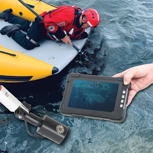 Northern Diver underwater search camera system with reach pole attachment displaying live fish footage on handheld monitor while a rescuer searches from an inflatable boat.