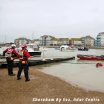 Rescue team members on the shore at Shoreham By Sea using a Northern Diver reach pole to assist a diver in the water.