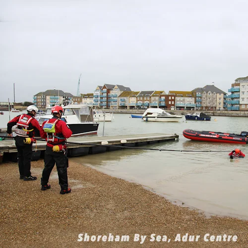Rescue team members on the shore at Shoreham By Sea using a Northern Diver reach pole to assist a diver in the water.
