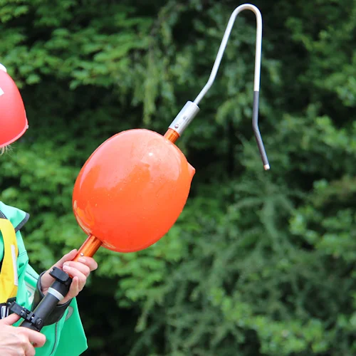 Rescue technician in red helmet holding the Northern Diver Inflatable Buoy Reach Pole Attachment fitted with narrow hook at the end.