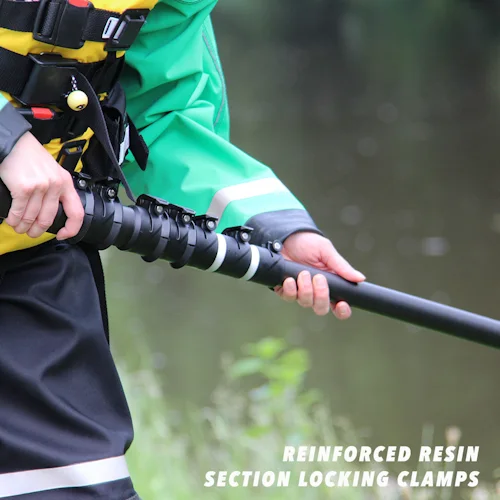 Rescuer's hands gripping a Northern Diver reach pole showing the reinforced resin section locking clamps near the riverbank.