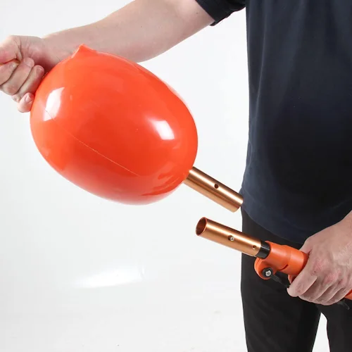 Person disconnecting the Northern Diver Inflatable Buoy Reach Pole Attachment from the copper-toned pole coupling, demonstrating the quick-release connection.
