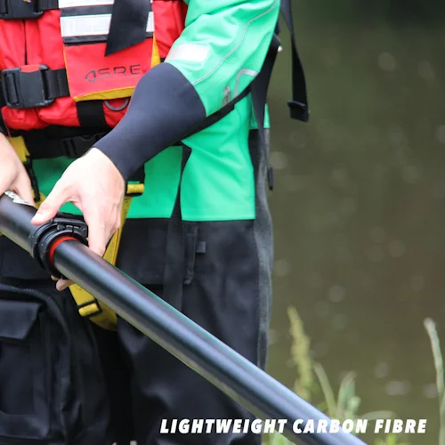Close-up of rescuer's hand gripping a lightweight carbon fiber Northern Diver reach pole near the riverbank.